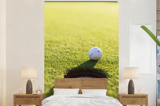 Behang – Fotobehang Golfbal ligt vlakbij de hole in het groene gras – Breedte 170 cm x hoogte 260 cm